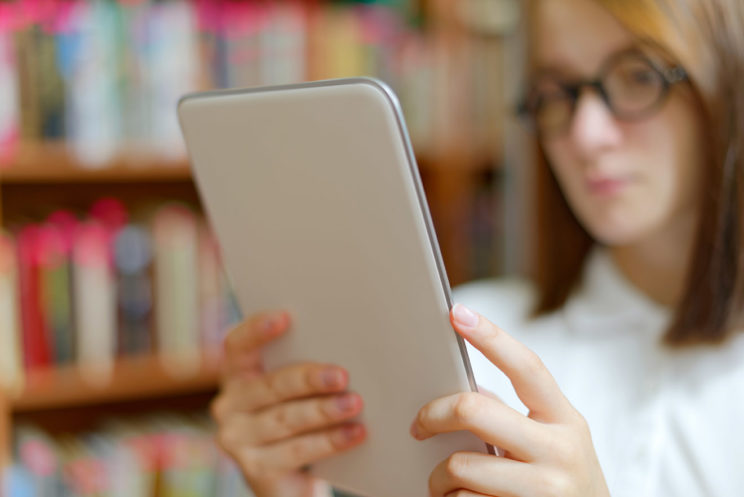 Nuori nainen lukemassa tekstiä tabletin näytöltä